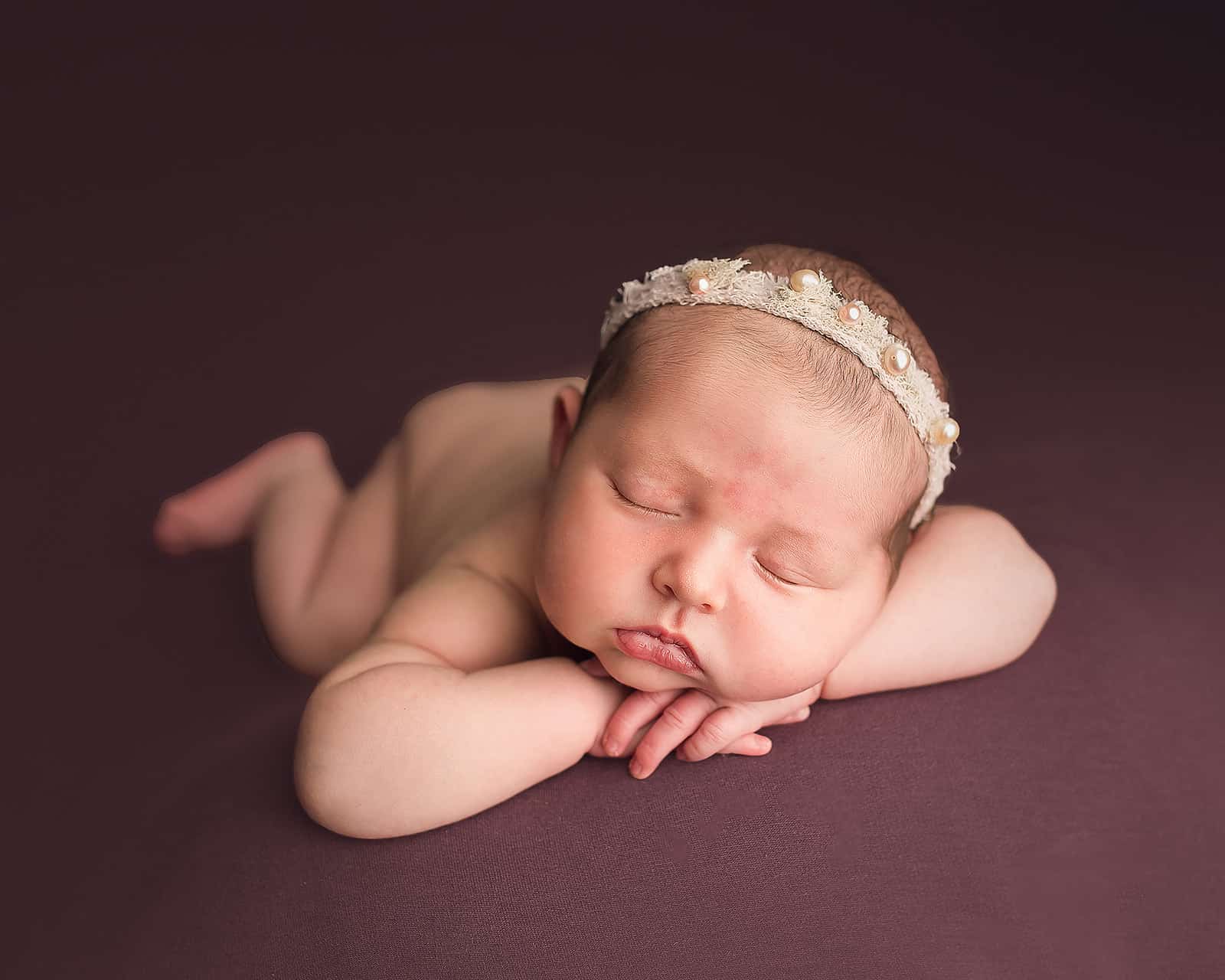 newborn baby girl in pearl headband sleeping on her hands Baby Stores in Grants Pass Oregon