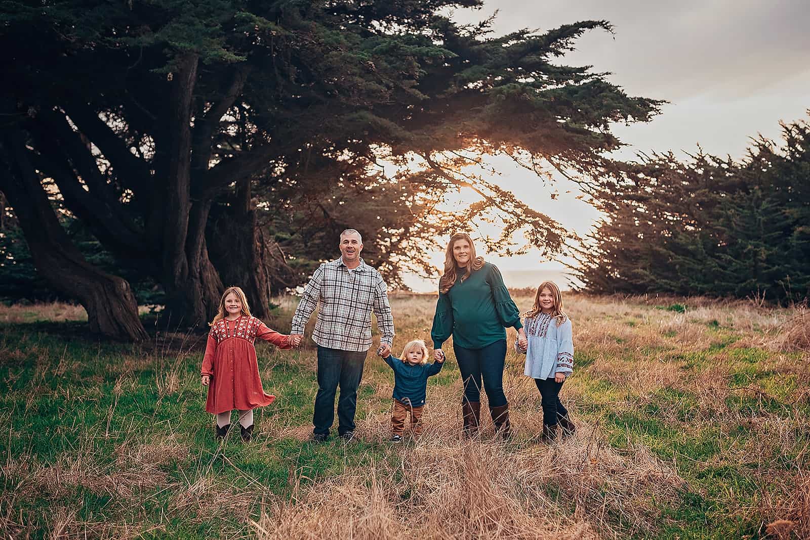 family of 5 holding hands and walking in a field at sunset Things to do in Medford OR