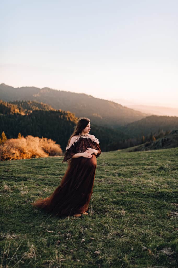 mom to be in brown gown in a field ashland yoga center