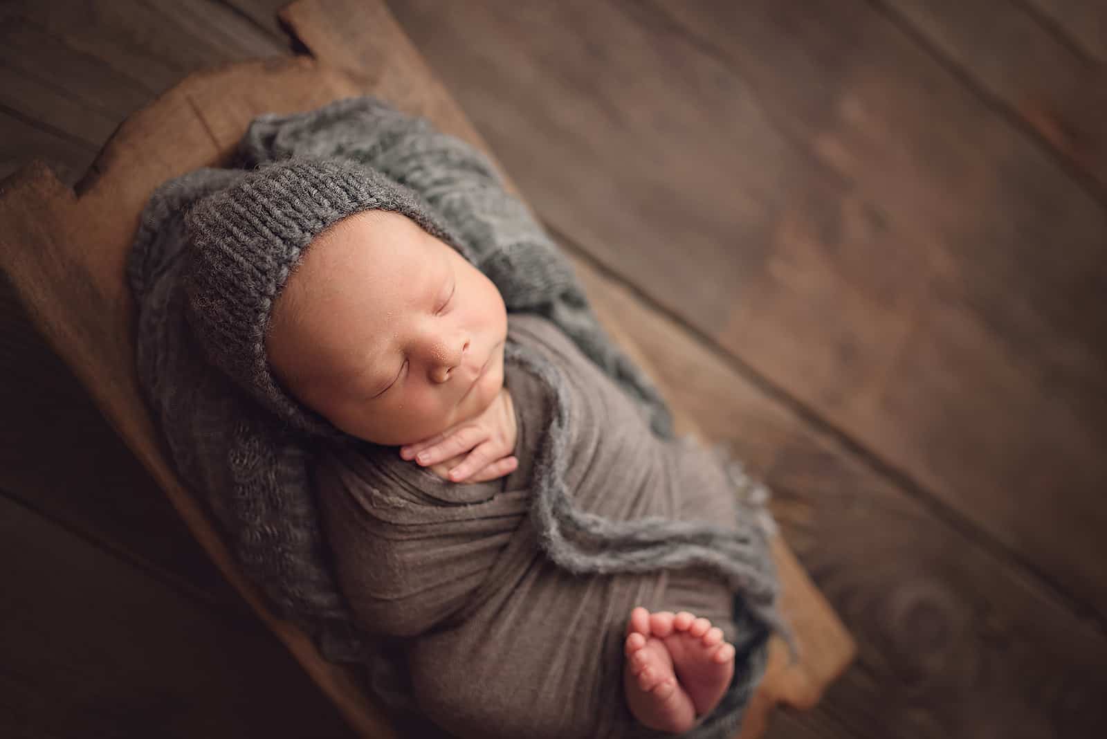 Baby wrapped in grey on wood floor
