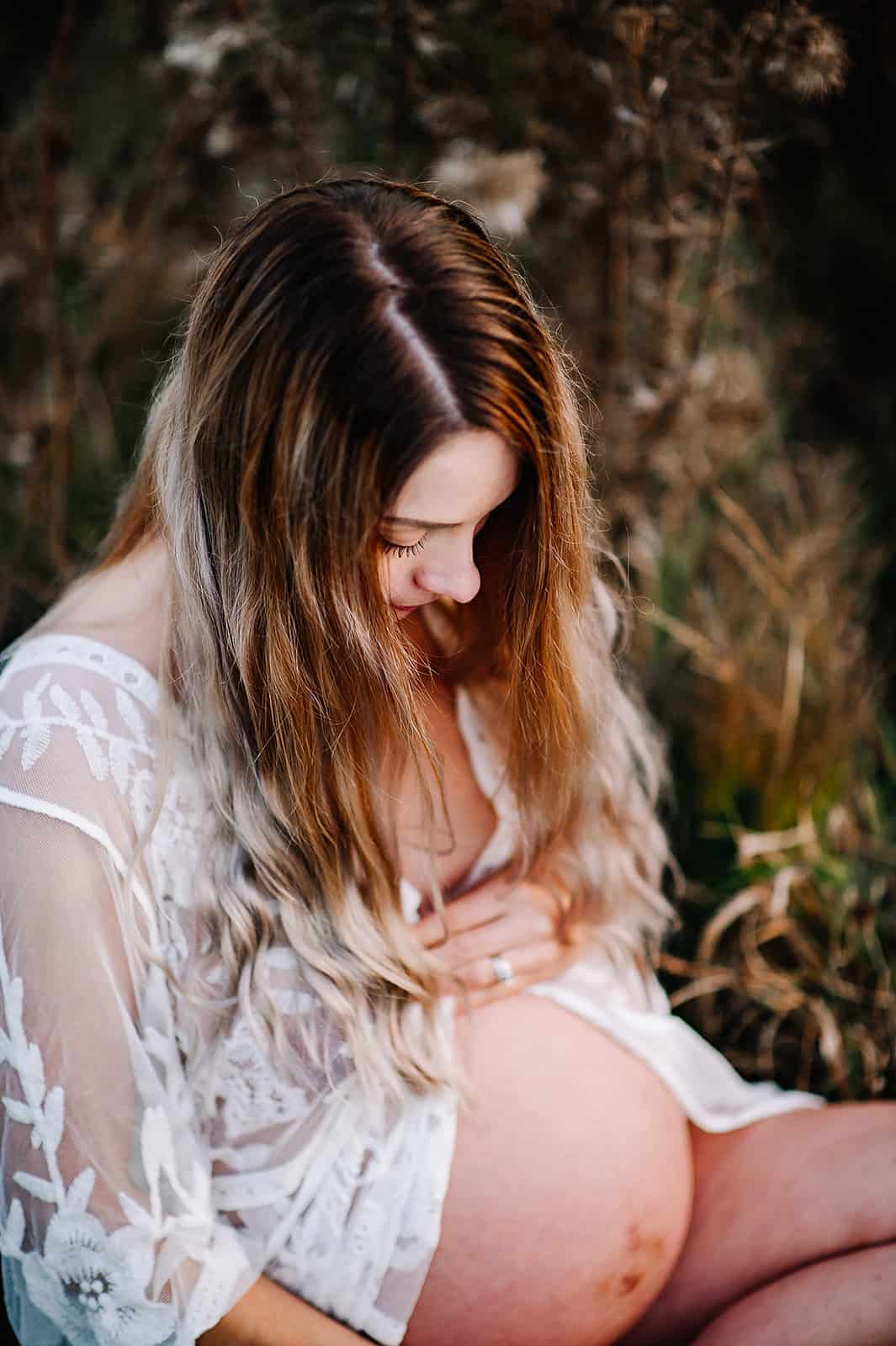 pregnant woman in white gown holding and looking at her belly Maternal Fetal Medicine Medford