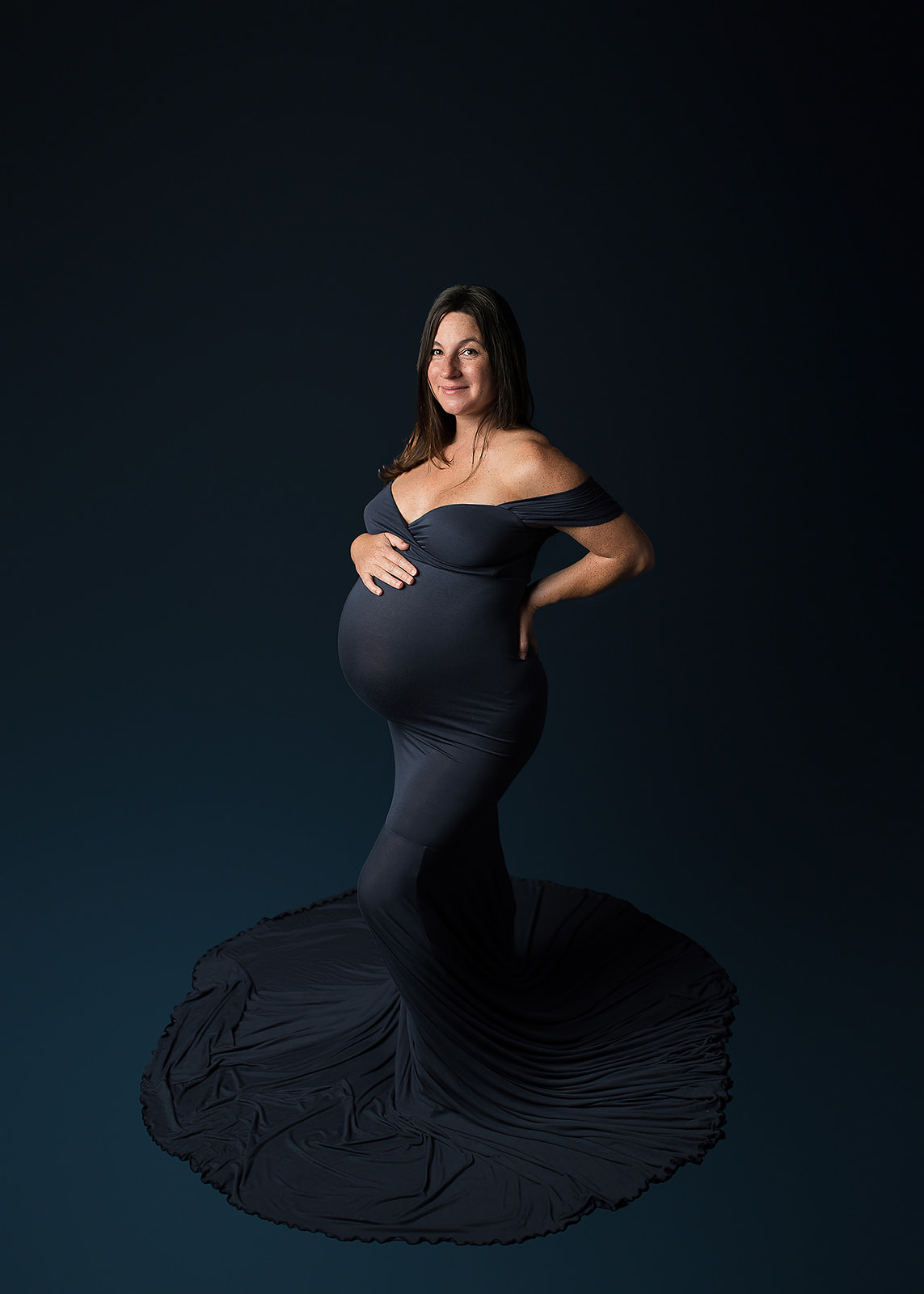 mom to be in navy maternity gown holding her bump Spas in Southern Oregon