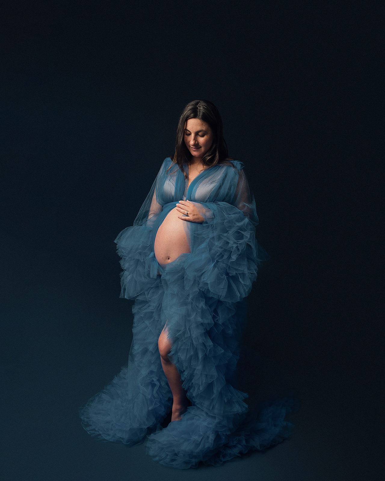 mom to be in blue maternity robe holding her bump
